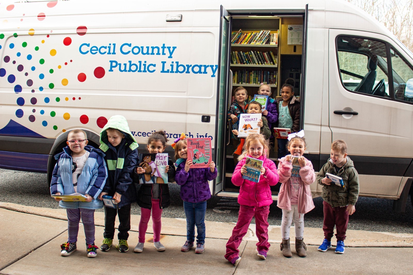 Outreach, Children outside of the mobile outreach van holding books.