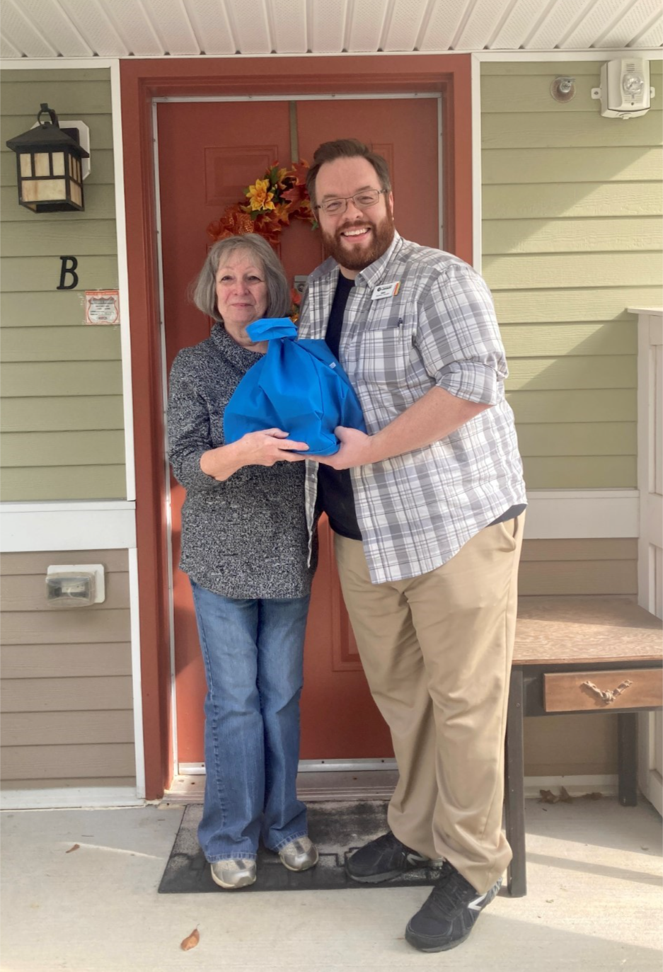 Photo of staff with a patron holding a book, homebound seniors